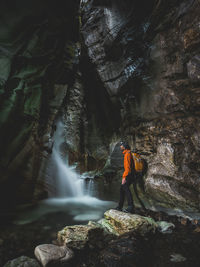 Man looking at waterfall while exploring cave