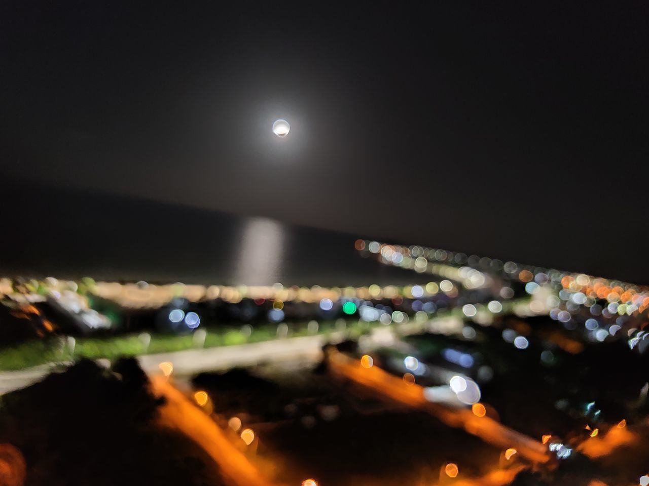 DEFOCUSED IMAGE OF ILLUMINATED CITY AGAINST SKY