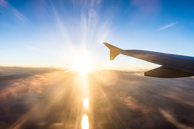 Airplane wing against sky during sunset