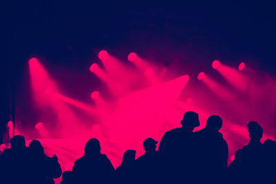 Silhouette of cheering crowd at a concert. colorful bright stage lights in the background