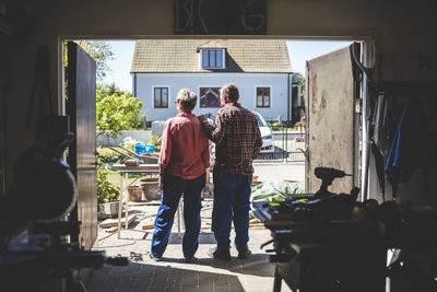 Senior couple looking at yard while standing in workshop