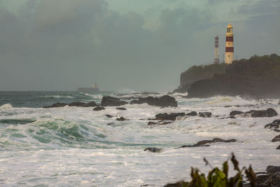 Lighthouse by sea against sky