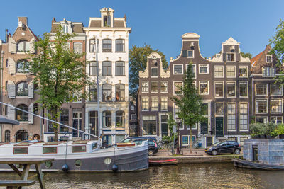 Sailboats moored on canal by buildings in city against sky