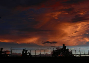 Silhouette man in the bridge against dramatic sky during sunset