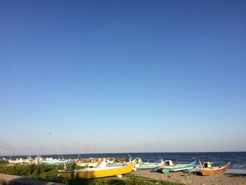 Boats on beach against clear blue sky