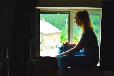 Side view of thoughtful woman sitting at window sill