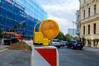 Road sign on street in city against sky