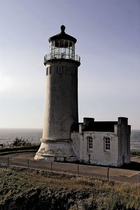 Lighthouse amidst buildings against sky