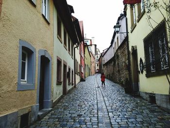 Rear view of man walking on cobblestone street