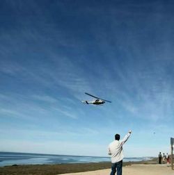 Rear view of man with airplane flying in sky