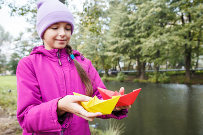 Smiling girl holding paper boat 