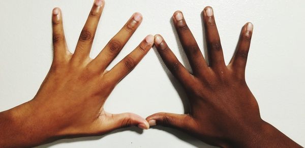 Close-up of hands touching hand over white background