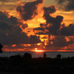 Scenic view of sea against dramatic sky during sunset