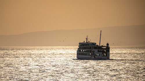 Boat in sea against sky during sunset