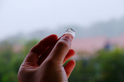 Close-up of hand holding crystal against blurred background