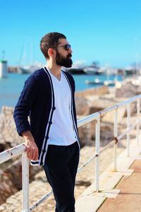 Young man standing by railing on bridge