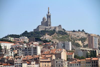 Low angle view of buildings against notre-dame de la garde