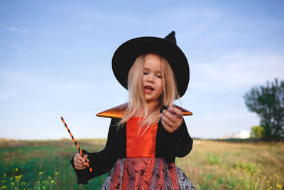 Portrait of smiling girl standing on field against sky