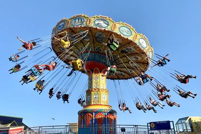 Low angle view of chain swing ride against sky