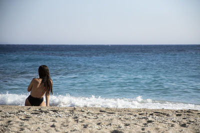 Rear view of man looking at sea against clear sky