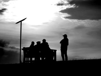 Silhouette people standing on land against sky at dusk