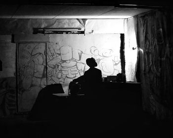 Silhouette man sitting in abandoned building