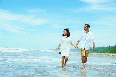 Full length of woman standing in sea against sky