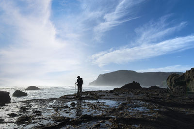 Man standing on rock on land against sky