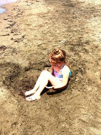 High angle view of girl sitting on sand at beach