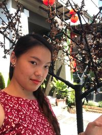 Portrait of smiling young woman against tree