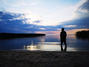 Rear view of man standing on beach during sunset