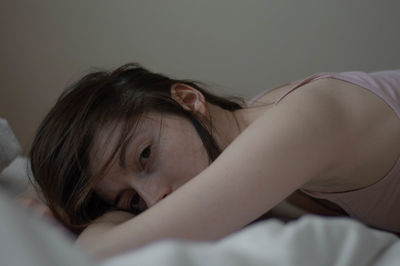 Portrait of woman lying down on bed at home