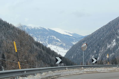 Road by mountains against sky during winter