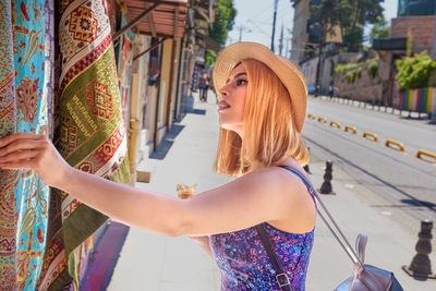 Woman wearing hat standing against built structure
