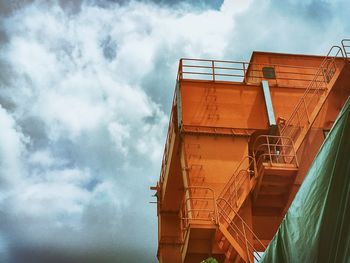 Low angle view of industry against cloudy sky