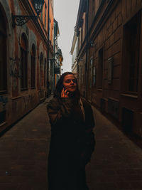 Woman standing on footpath amidst buildings in city