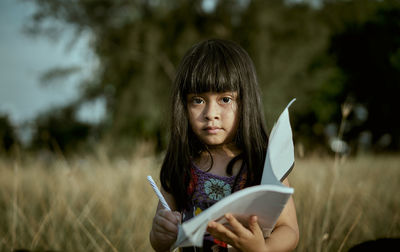 Portrait of girl studying on field