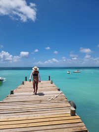 Rear view of man on pier over sea against sky