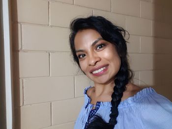 Portrait of smiling young woman by wall at home