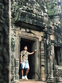 Full length portrait of woman standing against building