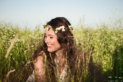 Smiling young woman amidst plants on land