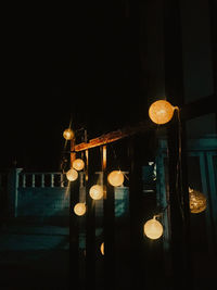 Low angle view of illuminated lights hanging on street at night