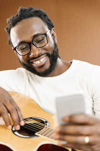 Smiling man using phone while sitting in studio