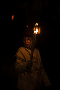 Man holding lit candle in the dark