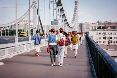 Rear view of people walking on footbridge in city