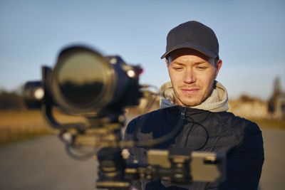 Portrait of man with camera standing outdoors