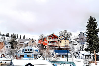 Snow covered houses and buildings against sky