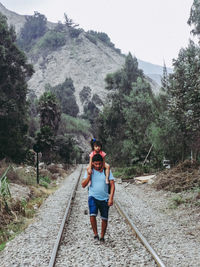 Rear view of man walking on railroad track