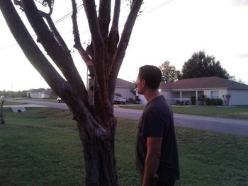 Rear view of man standing on tree trunk in field