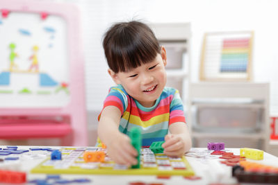 Cute girl playing with building blocks at classroom